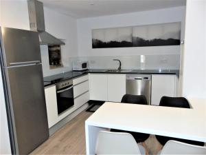 a kitchen with white cabinets and a white table and chairs at Casa da Fonte in Tarouca