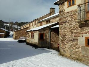 un edificio de ladrillo con nieve en el suelo al lado en Casa Do Grilo en Monfero