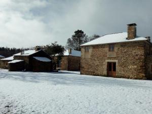 un edificio de piedra con nieve en el suelo en Casa Do Grilo en Monfero