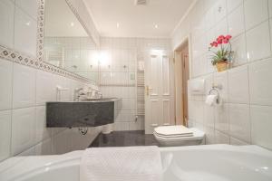 a white bathroom with a sink and a toilet at Hotel Residenz Rennhack in Prerow