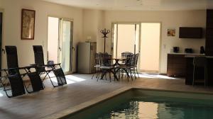 a living room with a pool and a table and chairs at Gîte Jet d'eau avec piscine intérieure 30 minutes Versailles in Montainville