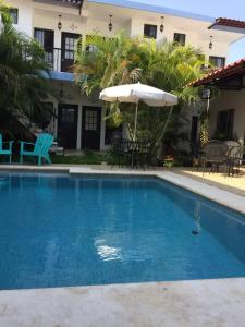 a swimming pool with an umbrella and a house at Casa Akbal B&B in Mérida