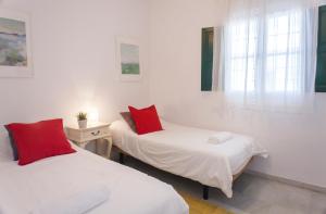 Camera bianca con 2 letti e cuscini rossi di Archeros Skyview by Valcambre a Siviglia