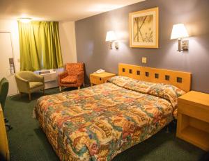 Habitación de hotel con cama y silla en Travel Inn en Phoenix