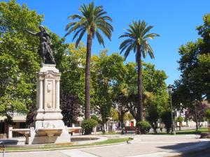 a statue of a woman in a park with palm trees at Casa Valientes B - Free private parking, patio, WiFi & AC in Jerez de la Frontera
