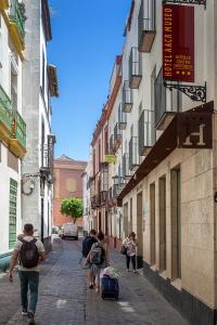 un grupo de personas caminando por una calle con equipaje en Hotel AACR Museo en Sevilla