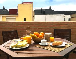 a wooden table with a bowl of fruit and orange juice at Ático cerca del mar in Valencia