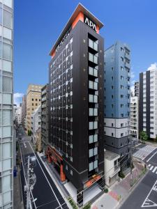 APA Hotel Hatchobori Shintomicho في طوكيو: مبنى اسود عليه لافته نيسان