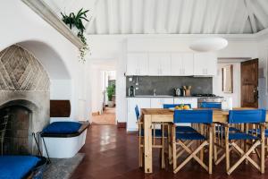 a kitchen with a table and chairs and a fireplace at OUTPOST - Casa das Arribas in Azenhas do Mar