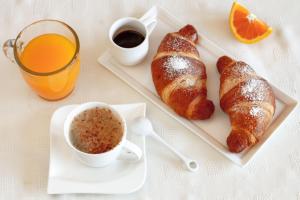 un desayuno con cruasanes y una taza de café y zumo de naranja. en Aiello Rooms, en Milán