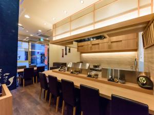 a restaurant with a bar with black chairs at APA Hotel Hatchobori Shintomicho in Tokyo