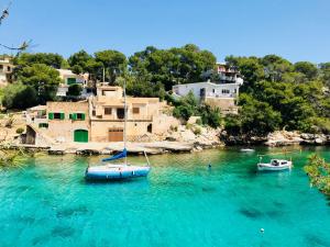 two boats in the water in front of houses at Apartaments Marina Sol i Pins in Cala Figuera