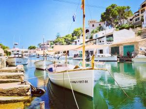 a sailboat docked in a harbor with other boats at Apartaments Marina Sol i Pins in Cala Figuera