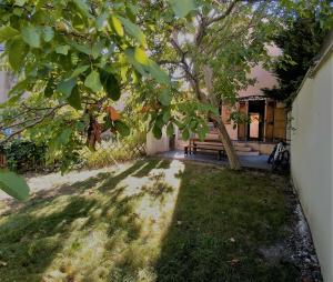 une maison avec un arbre et un banc dans une cour dans l'établissement MAISON JARDIN ET PARKING PRIVé dans GRENOBLE, à Grenoble