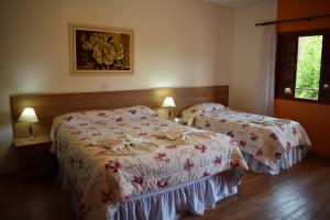 1 dormitorio con 2 camas y una foto en la pared en Pousada Recanto Feliz, en Campos do Jordão