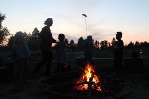 Un groupe de personnes debout autour d'un feu dans l'établissement Domek Zalesie, à Barczewo