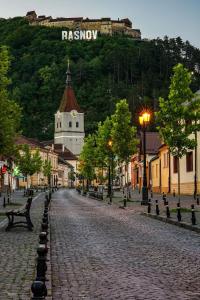 eine Kopfsteinpflasterstraße in einer Stadt mit einem Uhrturm in der Unterkunft Casa Lucky in Râșnov