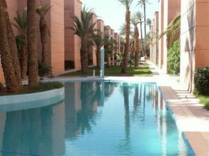 een zwembad met palmbomen naast een gebouw bij Dar Tariq 3 suites avec pisicine in Marrakesh