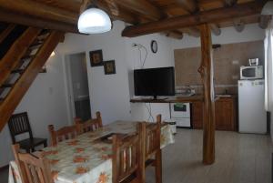 a kitchen and dining room with a table and a television at Cabañas Abelard in Esquel