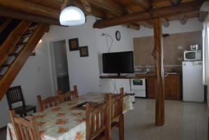 cocina y comedor con mesa y TV en Cabañas Abelard en Esquel