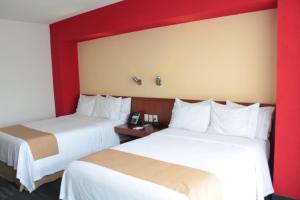 2 łóżka w pokoju hotelowym z czerwonymi ścianami w obiekcie Holiday Inn Express Guadalajara Expo, an IHG Hotel w mieście Guadalajara