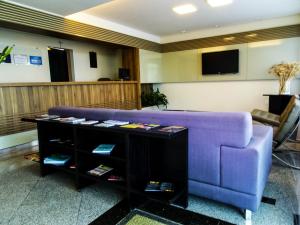 a living room with a purple couch and a tv at Sete Lagoas Residence Hotel in Sete Lagoas