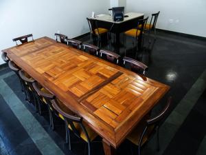 drewniany stół w pokoju z krzesłami wokół niego w obiekcie Sete Lagoas Residence Hotel w mieście Sete Lagoas