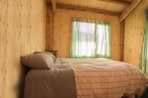 uma cama num quarto de madeira com uma janela em El Refugio Casa de Montaña em San Martín de los Andes