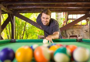 a man playing a game of pool with balls on a pool table at Redwood Beach Resort in Mechapa