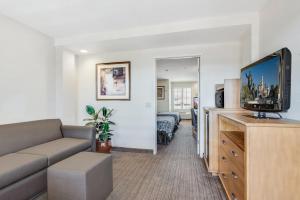 a living room with a couch and a flat screen tv at Anaheim Desert Inn & Suites in Anaheim