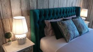 un letto con testiera verde, cuscini e lampada di Wherry Green Guest House (PRAIA DA BARRA)❤️ a Praia da Barra