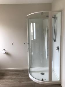 a shower with a glass enclosure in a bathroom at Jade Court Motel in Hokitika