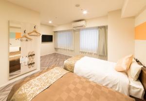a hotel room with two beds and a television at SARASA HOTEL Shin-Osaka in Osaka
