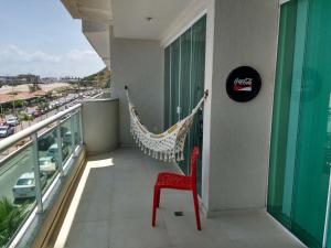 una silla roja sentada en un balcón con hamaca en Recanto do Pôr do Sol, en Arraial do Cabo