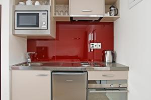 cocina roja con fregadero y microondas en Astra Motor Lodge en Hamilton