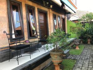 een veranda met stoelen en potplanten voor een gebouw bij Tegal Homestay in Sanur +21 foto's