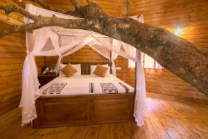 a bedroom with a canopy bed in a log cabin at La Pentera in Hambegamuwa