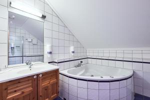 La salle de bains est pourvue d'une baignoire, d'un lavabo et d'un miroir. dans l'établissement Garder Hotell og Konferansesenter, à Gardermoen