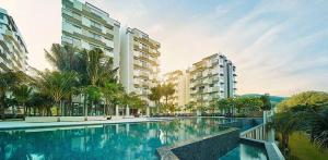 a large swimming pool with palm trees and buildings at By the sea Beach BABY in Batu Ferringhi