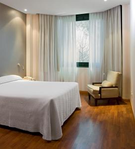 1 dormitorio con 1 cama, 1 silla y 1 ventana en Apartamentos TH Las Rozas, en Las Rozas de Madrid