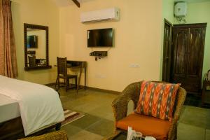 a bedroom with a bed and a chair and a television at Hathi Mauja in Jaipur