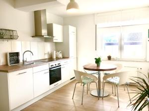 ヴィンターベルクにあるGLÜCKSKLEE 4 YOU WIFI - 72 qm- NATURE - SKI - FAMILIYの白いキャビネット、テーブルと椅子付きのキッチンが備わります。