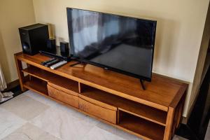 duży telewizor z płaskim ekranem siedzący na drewnianym centrum rozrywki w obiekcie Sea & City View Luxury Apartment w mieście Port Louis