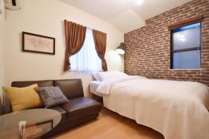 a bedroom with a bed and a couch and a brick wall at Origami Residential Suite - Tokyo Asakusa Skytree in Tokyo