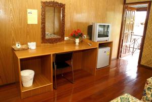 Habitación con escritorio, TV y espejo. en Duenshine Resort, en Kanchanaburi