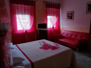 a bedroom with a bed and a couch and pink lighting at Villamir B&B in Albenga
