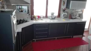cocina con nevera negra y alfombra roja en il Gelsomino appartamento turistico, en Pesaro