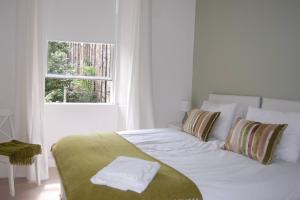 een wit bed in een witte kamer met een raam bij Home from Home at Number 2 in Edinburgh