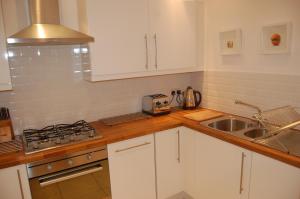 een keuken met witte kasten en een spoelbak bij Home from Home at Number 2 in Edinburgh