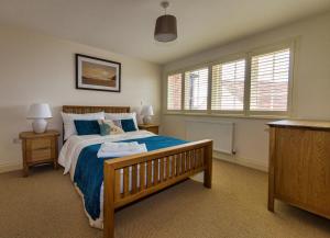 a bedroom with a bed with blue sheets and windows at Broads Reach in Stalham